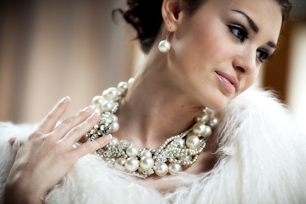 beautiful bride wearing a white fur shawl with a gorgeous pearl and beaded necklace and matching earrings - photo by North Carolina based wedding photographers Cunningham Photo Artists